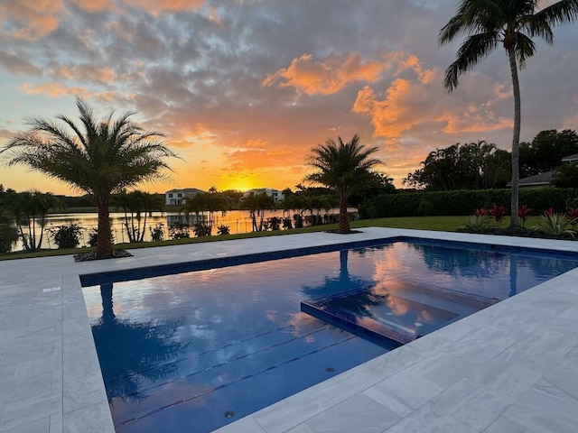 pool at dusk featuring a pool with connected hot tub