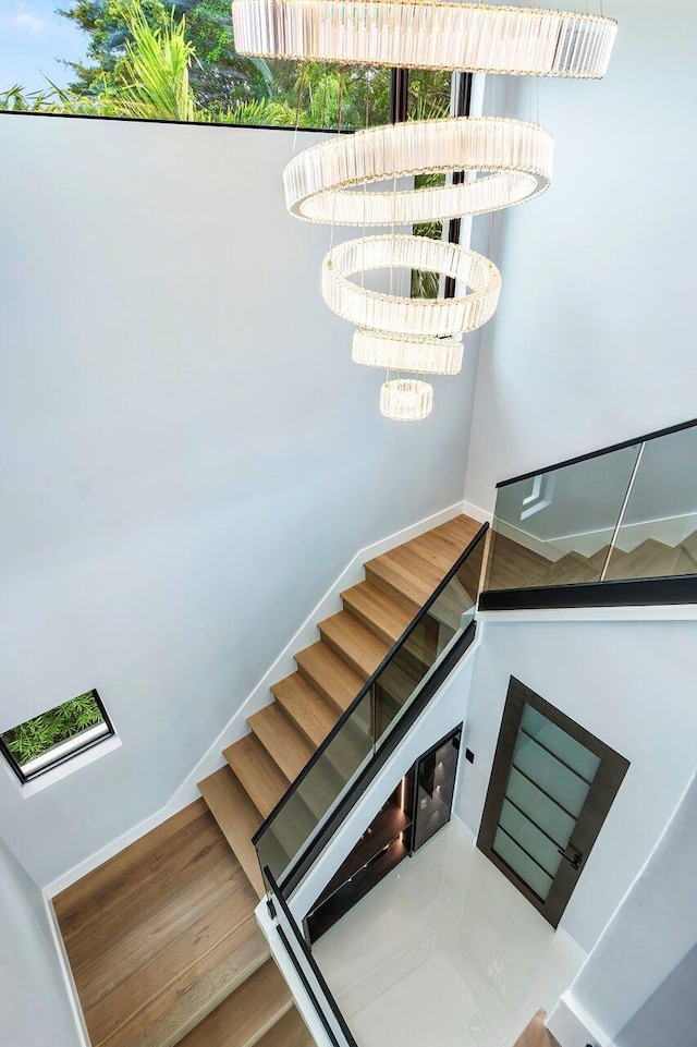 8387 Sawpine Rd, Delray Beach, FL 33446 - staircase featuring a chandelier, wood finished floors, and baseboards