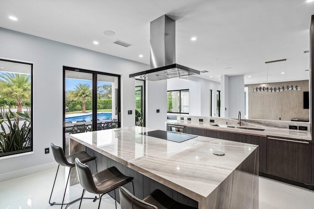 kitchen featuring light stone countertops, a spacious island, island exhaust hood, black electric stovetop, and modern cabinets