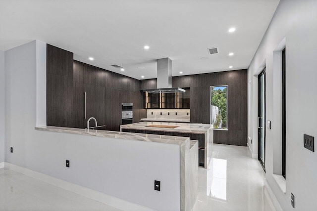 kitchen featuring visible vents, recessed lighting, a peninsula, island range hood, and modern cabinets