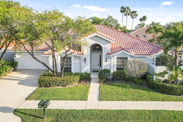 mediterranean / spanish house with an attached garage, stucco siding, concrete driveway, a front lawn, and a tile roof