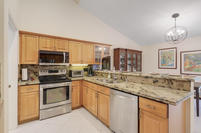 kitchen featuring a sink, light stone counters, appliances with stainless steel finishes, and a peninsula