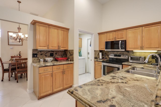 kitchen with light tile patterned floors, appliances with stainless steel finishes, light stone countertops, and a sink