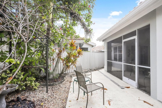 view of patio / terrace with fence and a sunroom