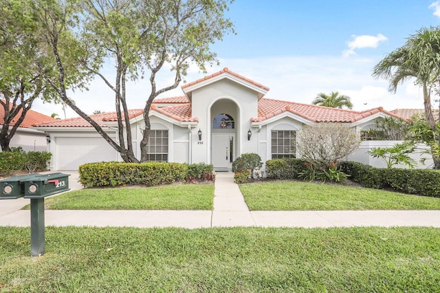 mediterranean / spanish house with stucco siding, a front yard, an attached garage, and a tiled roof