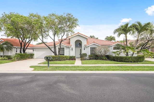 mediterranean / spanish-style home featuring a front yard, stucco siding, concrete driveway, a garage, and a tiled roof