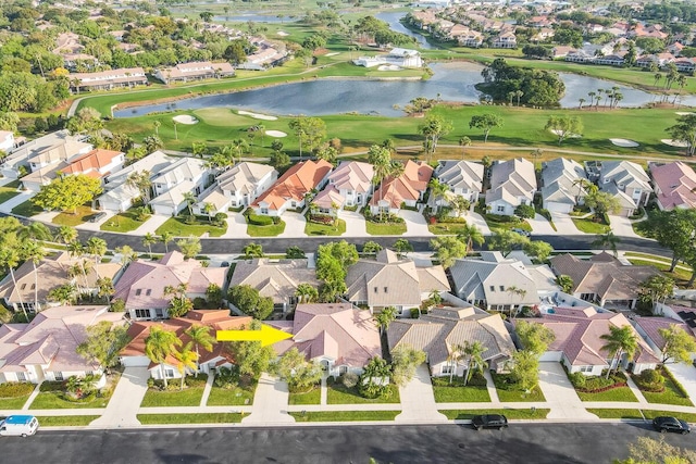 drone / aerial view featuring golf course view, a residential view, and a water view