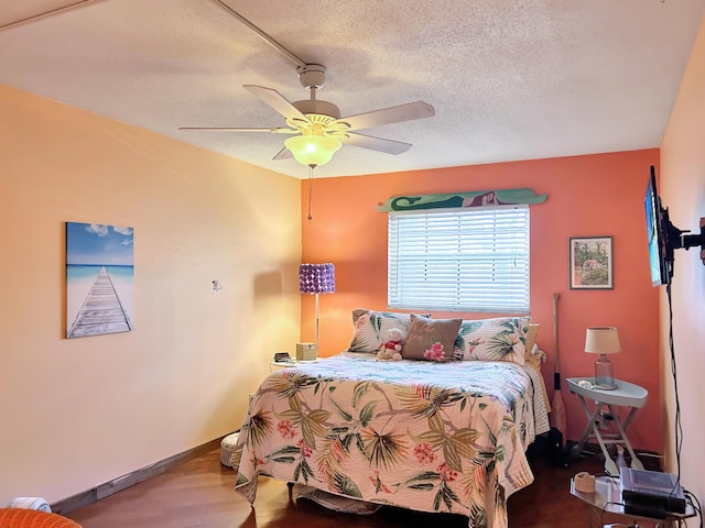 bedroom with a ceiling fan, wood finished floors, baseboards, and a textured ceiling