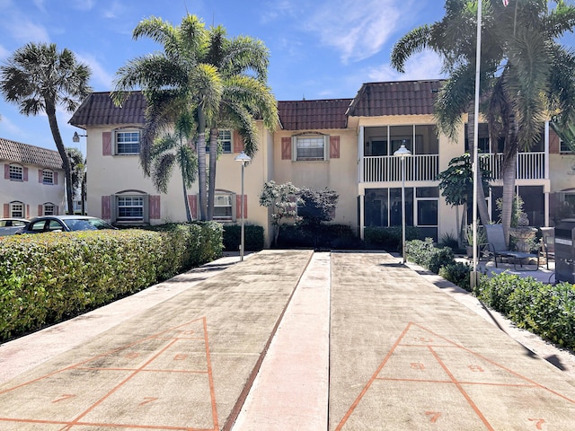 view of front of home featuring a tiled roof, stucco siding, and mansard roof