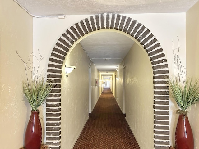 corridor with arched walkways and a textured ceiling