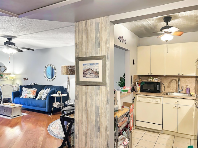 kitchen with a sink, a ceiling fan, black microwave, and white dishwasher