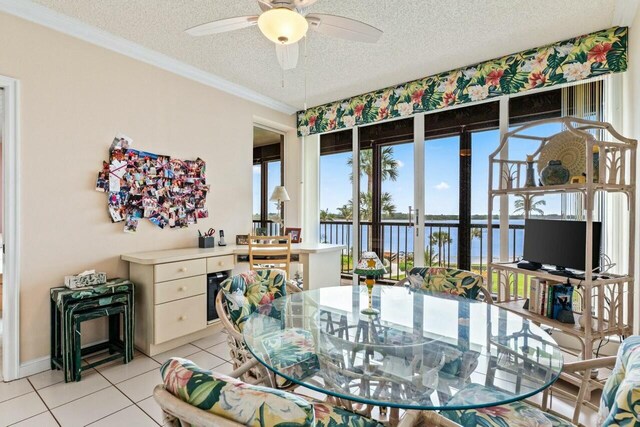 dining room featuring crown molding, light tile patterned floors, a ceiling fan, and a textured ceiling