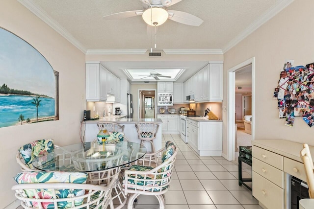 dining area featuring visible vents, ornamental molding, light tile patterned floors, a textured ceiling, and a ceiling fan