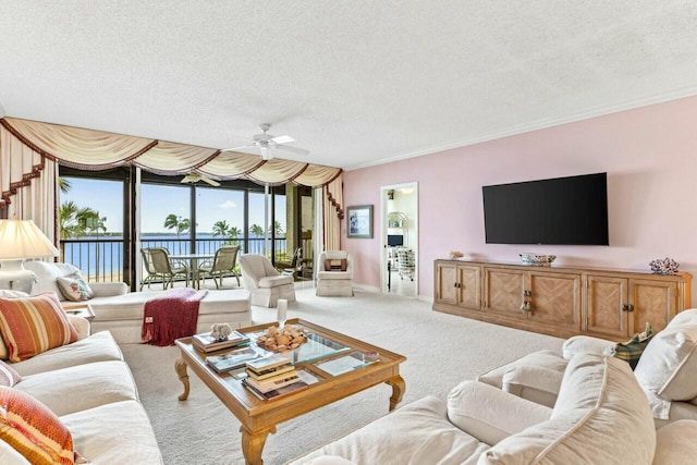 living room featuring light colored carpet, a textured ceiling, crown molding, and a ceiling fan