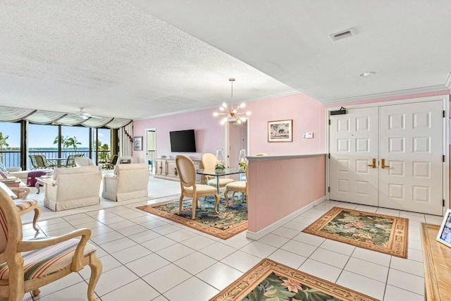 entrance foyer featuring light tile patterned floors, visible vents, ornamental molding, a textured ceiling, and a notable chandelier