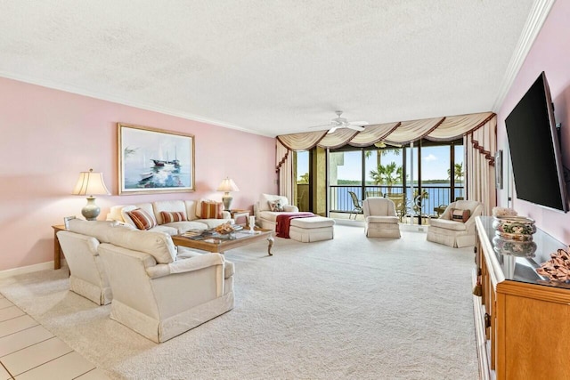 living area featuring carpet, baseboards, ceiling fan, ornamental molding, and a textured ceiling