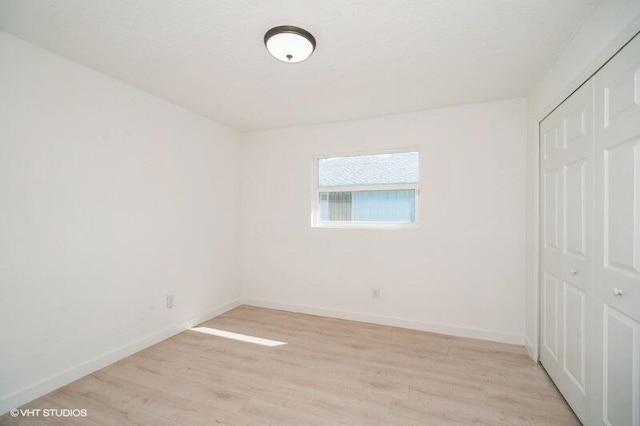 unfurnished bedroom featuring a closet, baseboards, and light wood-style flooring