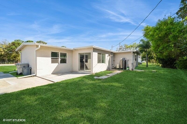 rear view of property featuring a yard, a patio area, and stucco siding