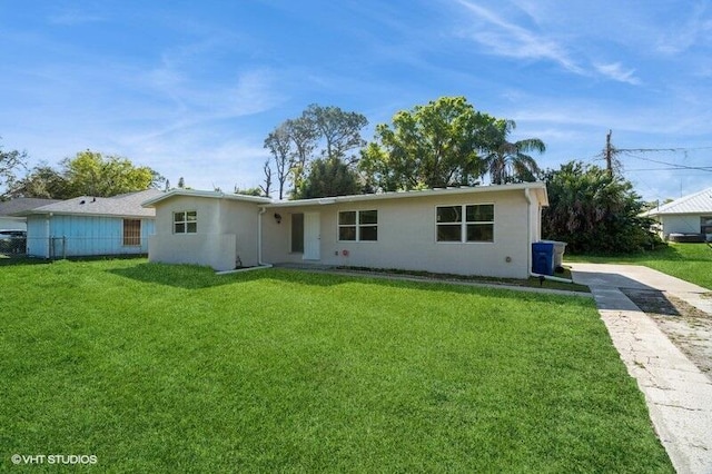 ranch-style house featuring a front lawn, fence, and stucco siding