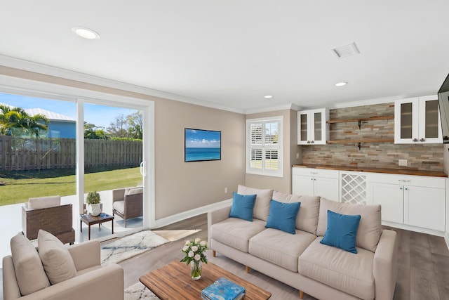 living room featuring visible vents, baseboards, ornamental molding, recessed lighting, and dark wood-style flooring