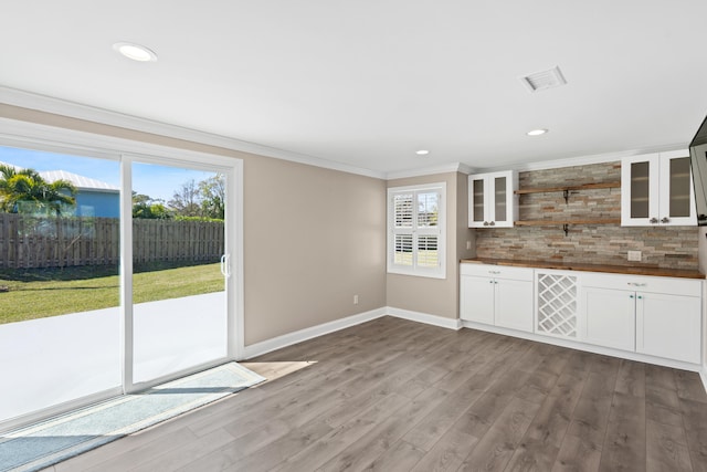 kitchen featuring glass insert cabinets, crown molding, decorative backsplash, wood finished floors, and open shelves