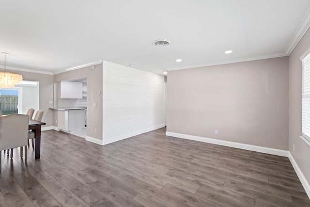 unfurnished room featuring visible vents, crown molding, an inviting chandelier, and dark wood-style flooring