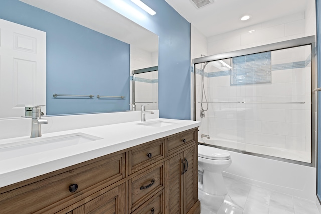 bathroom featuring double vanity, toilet, shower / bath combination with glass door, and a sink