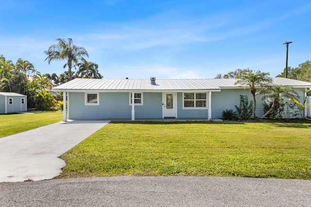 ranch-style house with driveway, metal roof, and a front yard