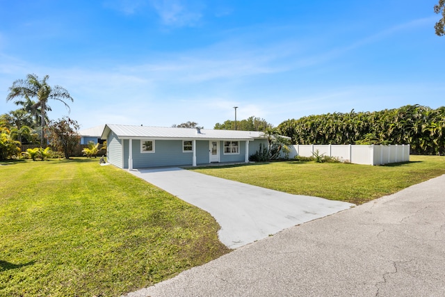 single story home featuring a front yard, fence, driveway, and metal roof