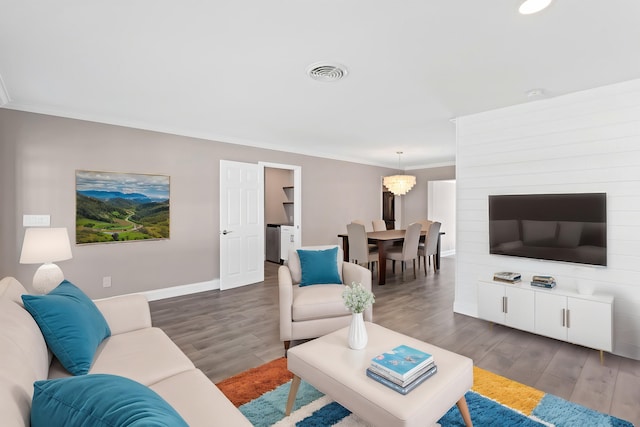 living room with visible vents, baseboards, dark wood finished floors, a chandelier, and ornamental molding