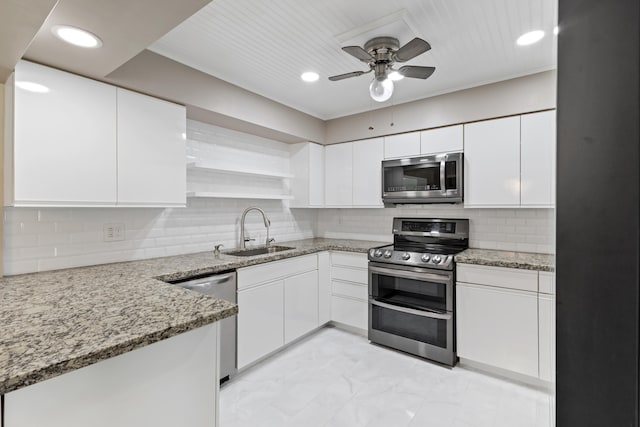 kitchen featuring appliances with stainless steel finishes, light stone countertops, open shelves, and a sink