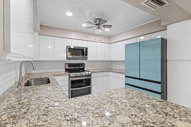 kitchen featuring light stone countertops, visible vents, a sink, decorative backsplash, and stainless steel appliances