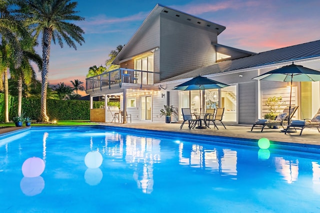 pool at dusk featuring a fenced in pool and a patio area