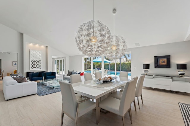 dining room featuring light wood-type flooring and high vaulted ceiling