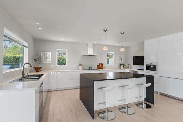 kitchen with a sink, white cabinets, black electric stovetop, wall chimney exhaust hood, and modern cabinets