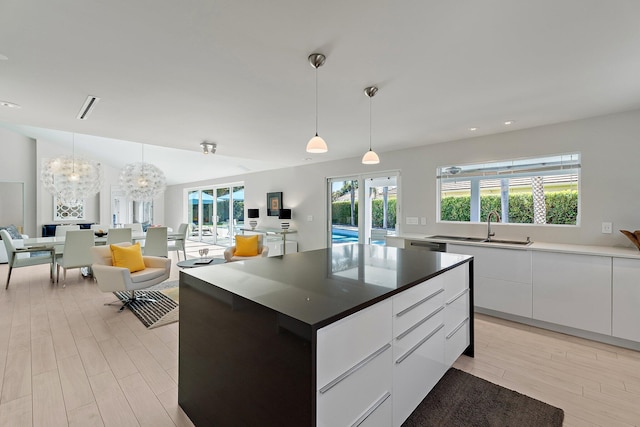 kitchen featuring a sink, lofted ceiling, open floor plan, and white cabinets