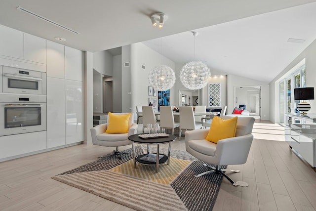 living area with lofted ceiling, light wood-style flooring, and a chandelier