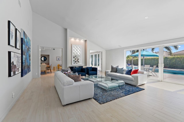 living area with high vaulted ceiling, light wood-type flooring, and baseboards