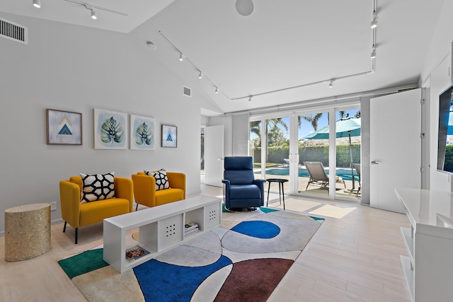 living area featuring visible vents, lofted ceiling, wood finished floors, and rail lighting