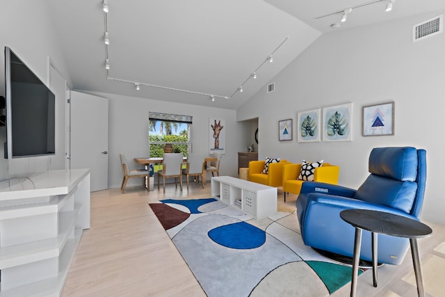 living room with track lighting, light wood-type flooring, visible vents, and vaulted ceiling