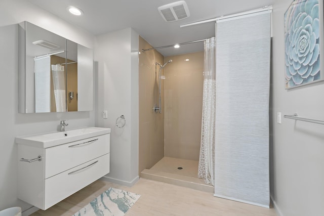 bathroom featuring visible vents, tiled shower, vanity, and baseboards