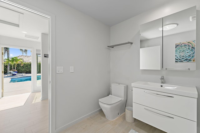 bathroom featuring vanity, toilet, wood finished floors, and baseboards