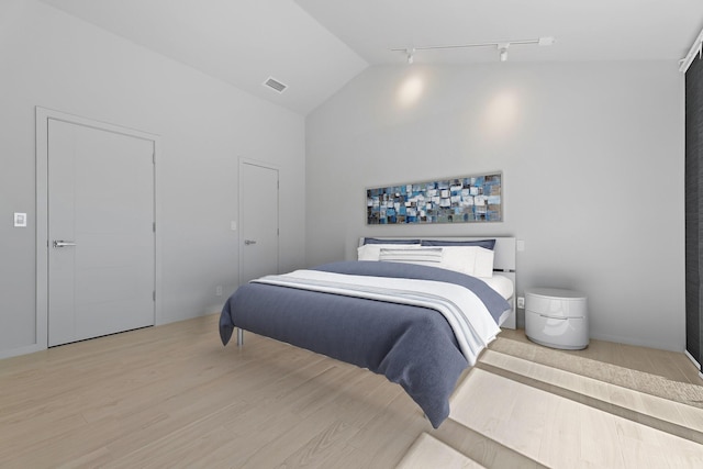 bedroom with wood finished floors, visible vents, and high vaulted ceiling