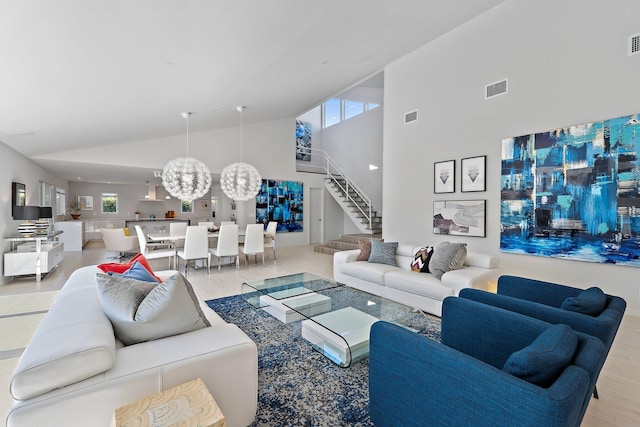 living room featuring a notable chandelier, visible vents, a healthy amount of sunlight, and stairs