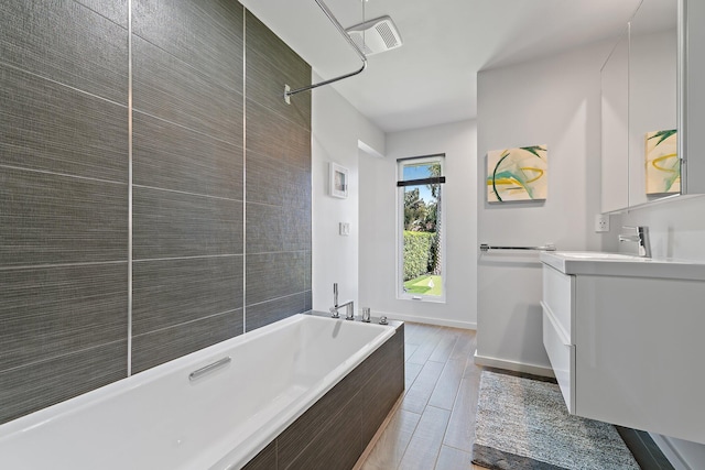 bathroom with vanity, baseboards, visible vents, wood tiled floor, and a bath