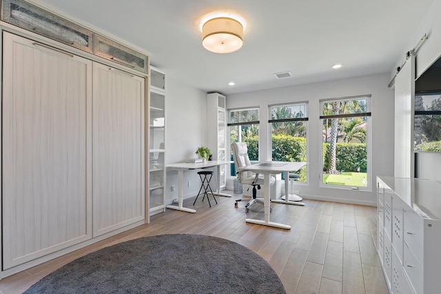 office space featuring wood finished floors, visible vents, baseboards, recessed lighting, and a barn door