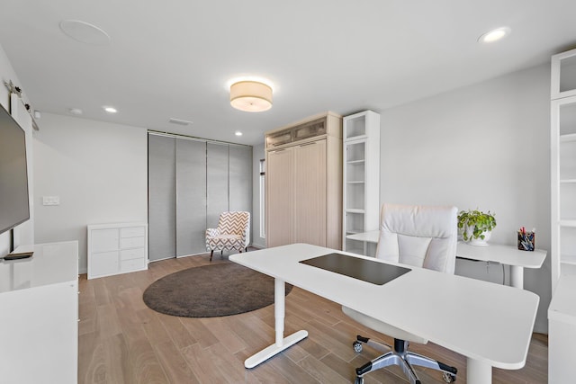 office with a barn door, recessed lighting, and light wood-style floors