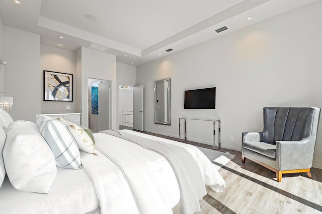 bedroom with visible vents, baseboards, a tray ceiling, recessed lighting, and wood finished floors