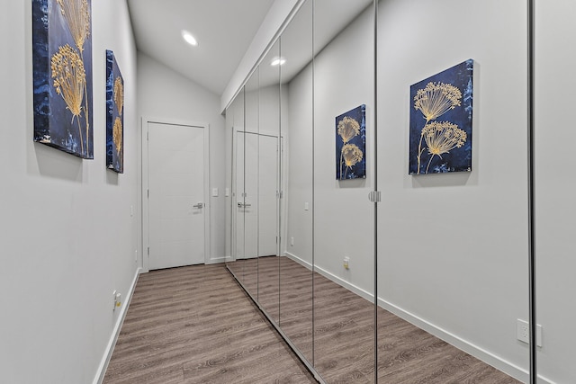 hallway with recessed lighting, baseboards, wood finished floors, and vaulted ceiling