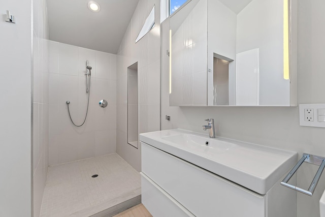 bathroom with tiled shower and vanity